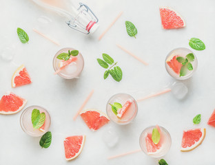 Flat-lay of cold refreshing summer alcohol cocktail with fresh grapefruit, mint and ice over white...
