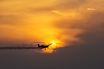 Fototapeta na wymiar Silhouette of airplane on sunset with smoke in background