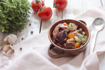 Cassoulet. Containing meat pork sausages, goose, duck and sometimes mutton and two types of white beans. French food. On old wooden white background.