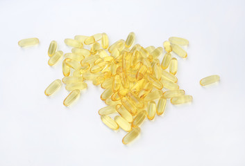 Yellow fish oil capsules on a white background.