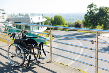 Fototapeta na wymiar Black new wheelchair left on a terrace