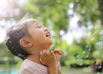 Cute little girl playing bubble in the garden.