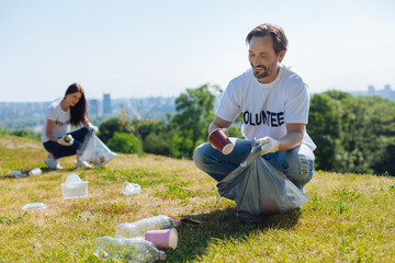 Focused motivated man cleaning local park from litter