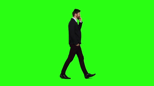 Businessman walks down the street, puts his hand in his pocket and talk phone. Green screen. Slow motion