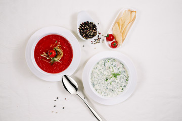 Two soups of okroshka and tomato soup on a wooden table, top view