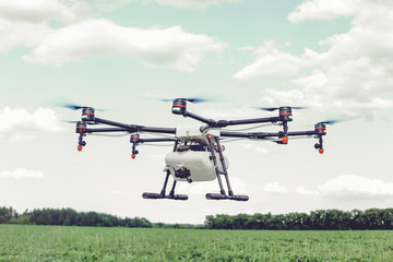 Professional agriculture drone flying and green wheat field, Hovering drone flies in blue sky and...