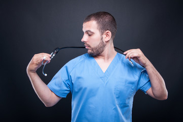 Doctor wearing scrubs putting on his stethoscope