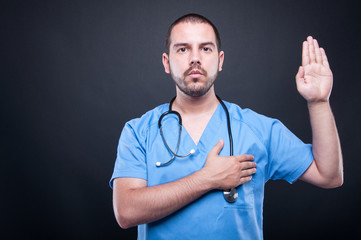 Portrait of male doctor with stethoscope taking oath