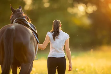 Poster de jardin Léquitation Backview of young woman walking with her horse in evening sunset light