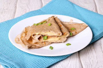 Two pancakes filled cheese with green onion on a white plate