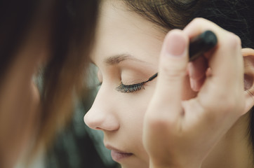 Obraz premium The make-up master paints the eyes of the girl. Makes makeup, close-up.