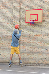 Obraz na płótnie Canvas back view of young man playing basketball alone
