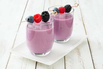 Healthy berry smoothie in glass on white wooden table
