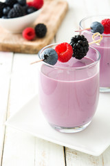 Healthy berry smoothie in glass on white wooden table
