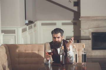 Man sitting on sofa with martini glass and three bottles