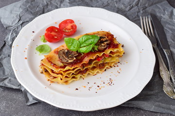 Vegetarian lasagna with mushrooms, onions, olives and tomato sauce on a white plate. Healthy eating concept. Mediterranian lifestyle