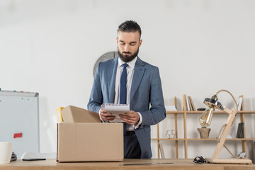 portrait of fired sad businessman packing office supplies at workplace