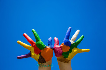 Painted kids hands isolated on blue sky backgrobnd