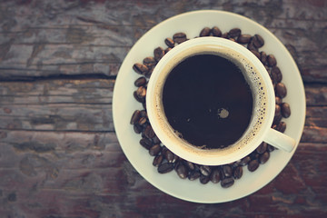 Black coffee in the cup on old wood table (top view) - vintage color effect