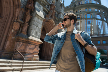 Happy youthful man with beard touring around city sights