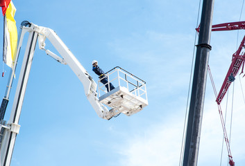 Hydraulic lift platform with bucket of yellow construction vehicle, heavy industry, blue sky and white clouds on background