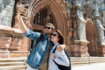 Cheery youthful lady and bearded guy using gadget on vacation