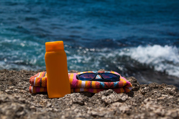 Obraz premium Summer, blue sea, beach towel, sunscreen and glasses