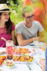 Group of friends lunching in the garden, focus on dishes