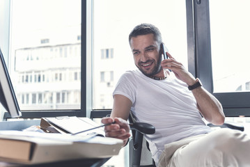 Fototapeta premium Cheerful mature man is talking on smartphone with pleasure
