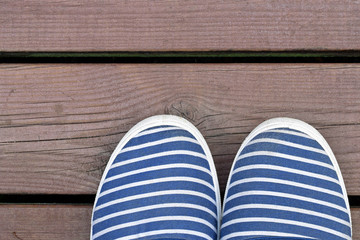 Sailor style blue and white striped shoes on wooden dock..
