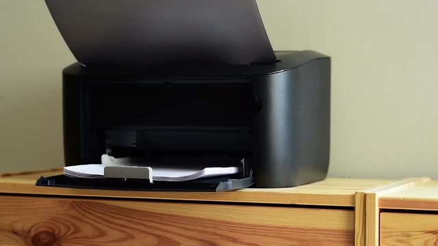 Compact small home office laser printer is printing documents on A4 paper