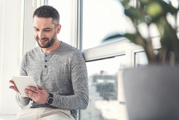 Joyful successful employee is enjoying modern gadget