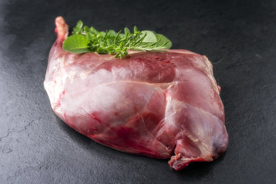 Raw Haunch of Venison as with herbs as close-up on a slate slab