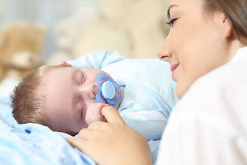 Mother watching her baby sleeping on bed