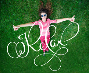 beautiful young woman lying on the green grass in the Meadow and calligraphy lettering word Relax