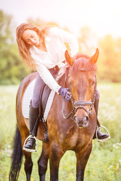 Young rider girl bent toward horse for complimenting it