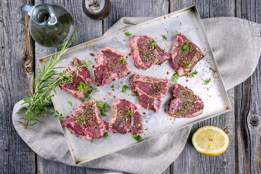 Raw T-Bone Lamb Steak with Seasonings as top view on a wooden table