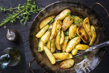 Roast Potatoes with herbs as top view in an iron cast pan