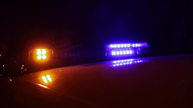 Luces Intermitentes de advertencia lanzando flash de colores en coche de la policia por la noche