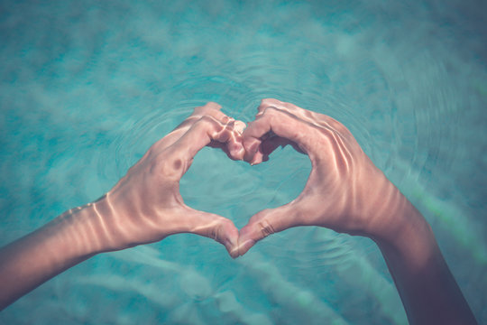 Female Making Heart Shape With Hands In Water