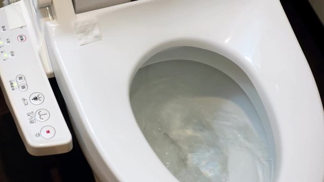 Toilet bowl with electronic control bidet. Water sprays from toilet bowl. A cleansing jet of water designed to cleanse the anus of the user of this bidet-style toilet. Hygiene procedure on toiletries.
