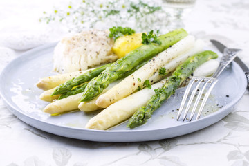 Codfish Fillet with green and white Asparagus and boiled Potatoes as top-view on a plate