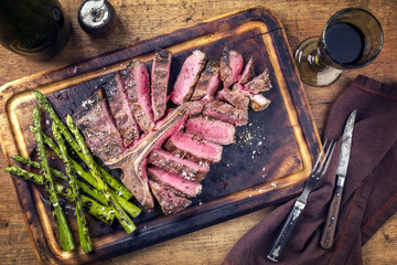 Barbecue dry aged Wagyu Porterhouse Steak sliced with green Asparagus on a cutting board