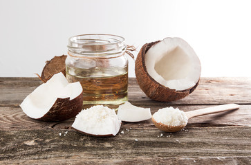 Half of coconut, pieces of coconut, coconut flakes and coconut glaas jar