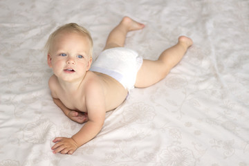 Cute blonde one year kid lying in the bed and looking up. Top view
