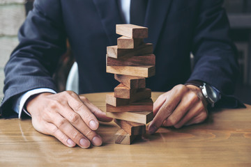 Alternative risk concept, plan and strategy in business, Risk To Make Buiness Growth Concept With Wooden Blocks, Images of hand of businesspeople placing and pulling wood block on the tower