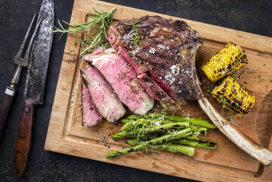 Barbecue Wagyu Tomahawk Steak with green Asparagus and Corn as top view on a cutting board