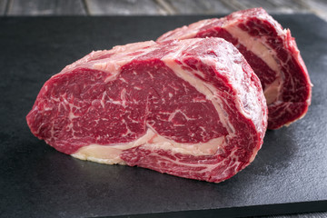 Two raw dry aged Kobe Entrecote Steak as close-up on a slate