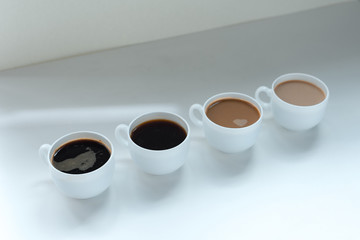 different kinds of coffee in row on white table, close-up view