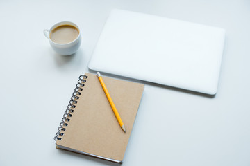 Laptop computer, notepad with pencil and cup of coffee isolated on white